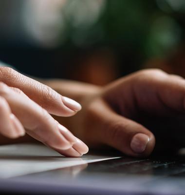 A photograph of a person typing on a laptop